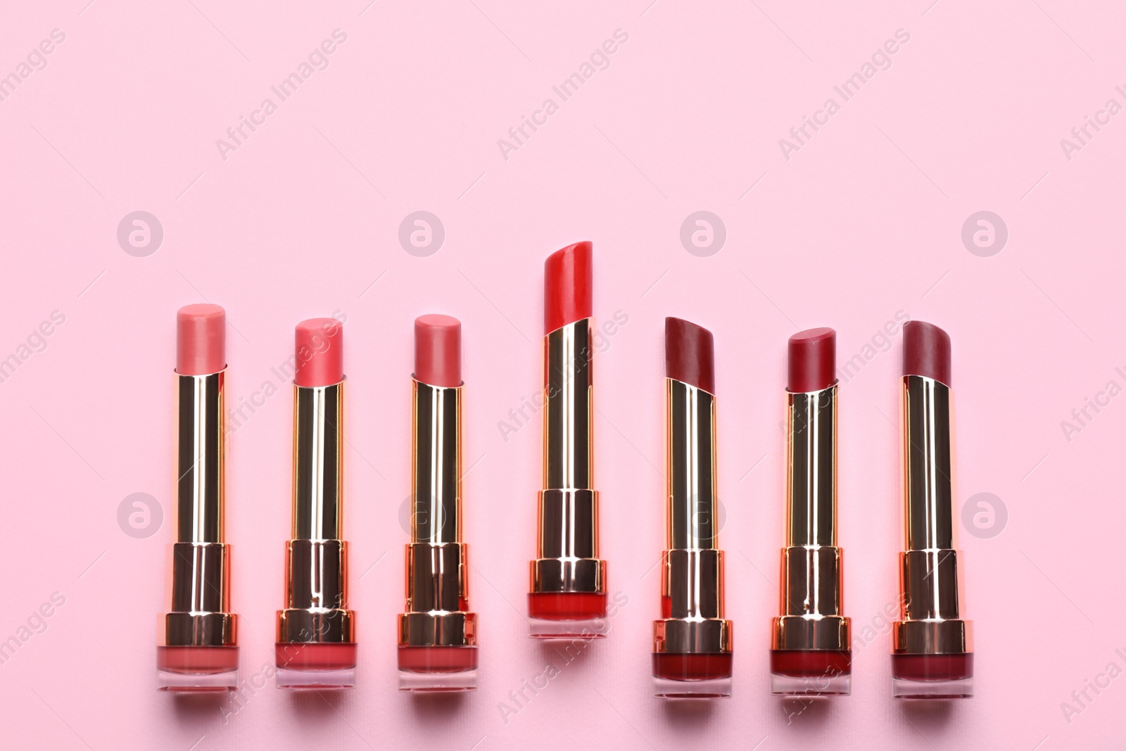 Photo of Different lipsticks on pink background, flat lay