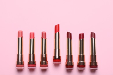 Photo of Different lipsticks on pink background, flat lay