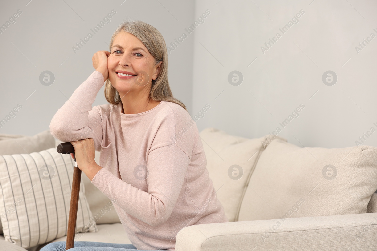 Photo of Mature woman with walking cane on sofa indoors