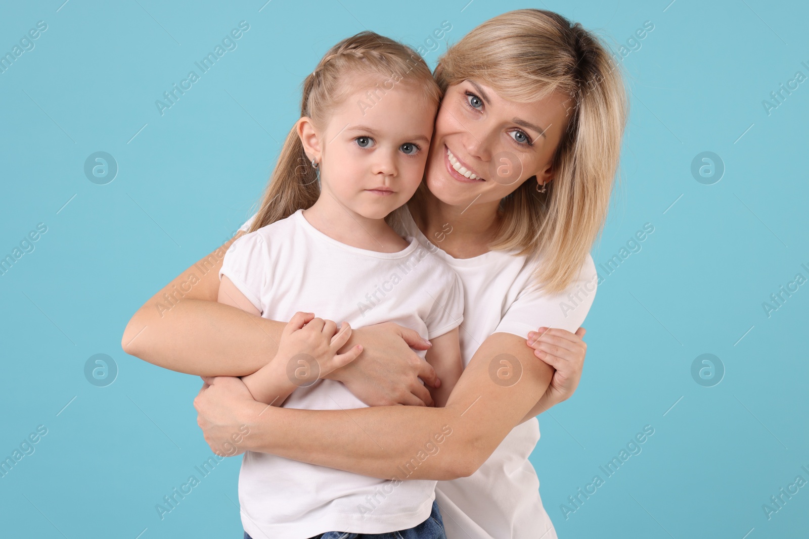 Photo of Family portrait of happy mother and daughter on light blue background