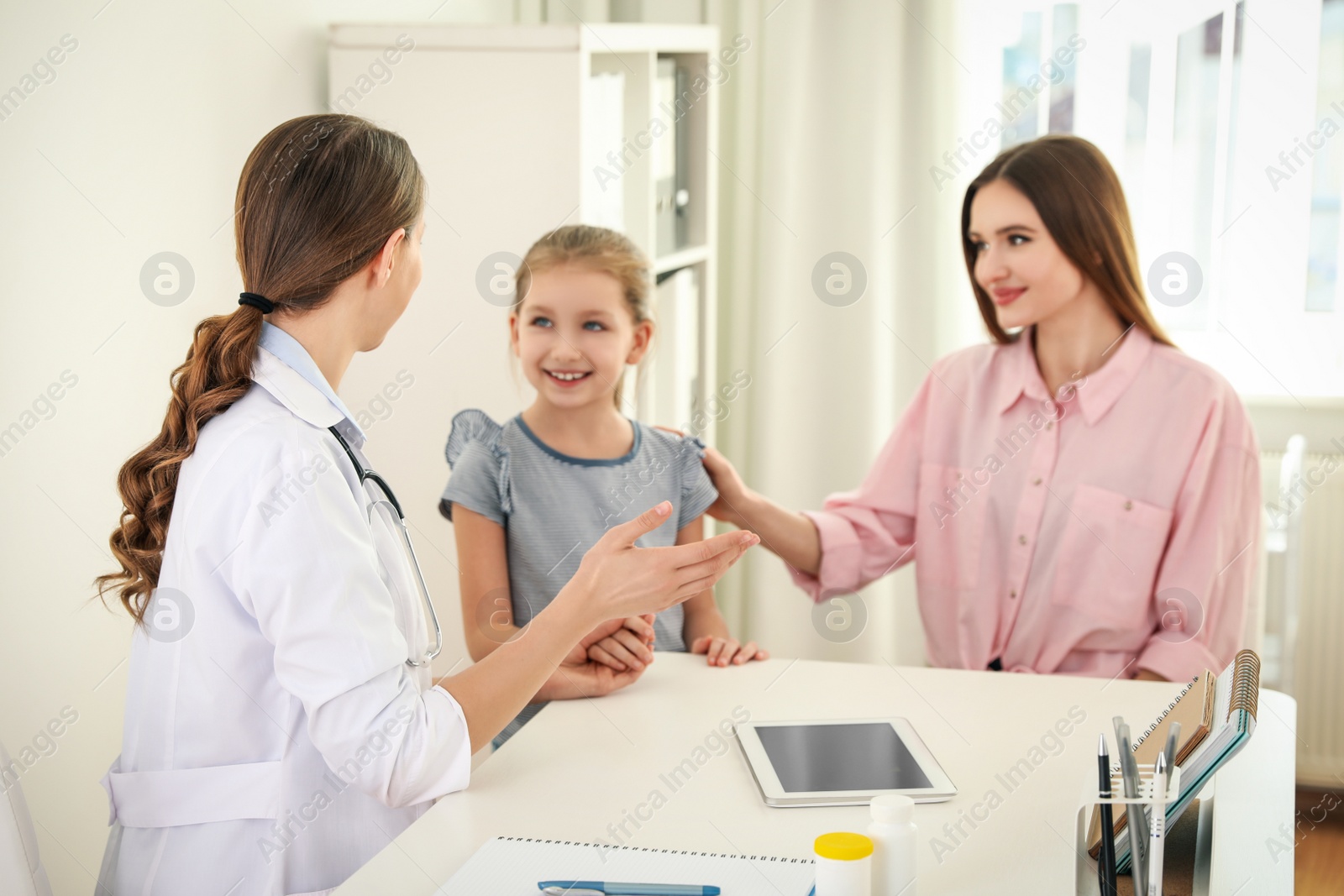 Photo of Mother and daughter visiting pediatrician. Doctor working with patient in hospital