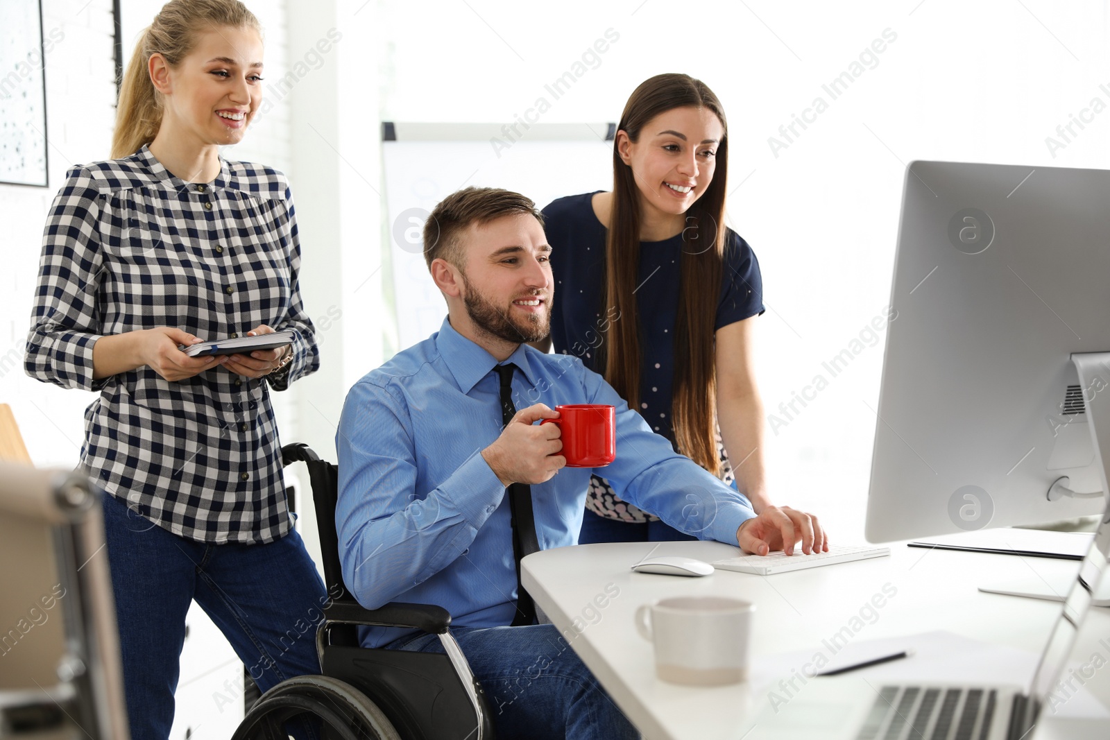 Photo of Man in wheelchair with his colleagues at workplace