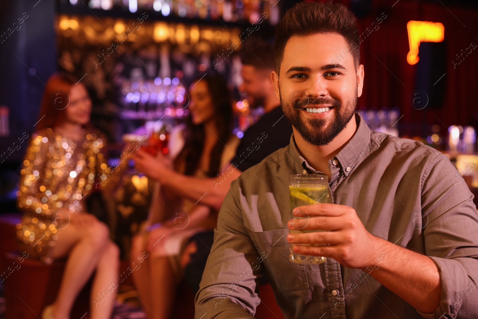 Photo of Friends spending time together in bar. Handsome man with fresh alcoholic cocktail, space for text