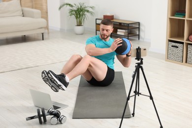 Photo of Trainer with ball streaming online workout on phone at home