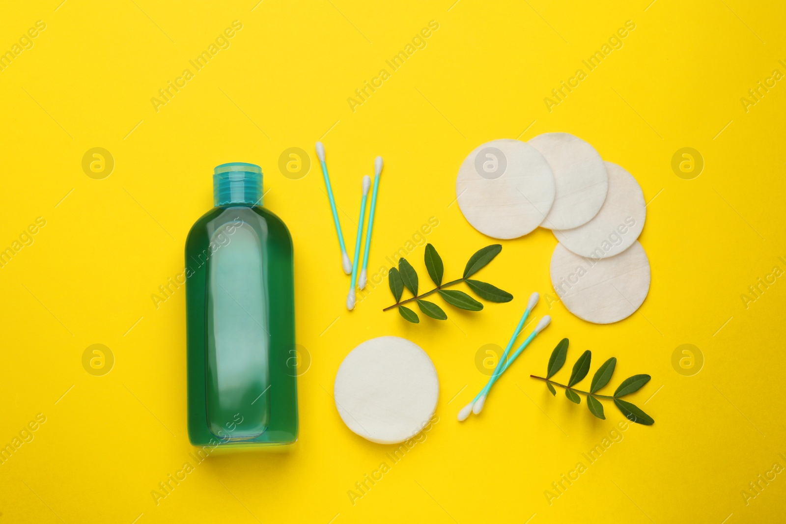 Photo of Cotton pads, swabs and makeup removal product on yellow background, flat lay