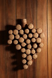 Photo of Grape made of wine bottle corks on wooden table, top view