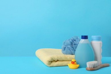 Baby cosmetic products, bath duck, accessories and towel on light blue background. Space for text