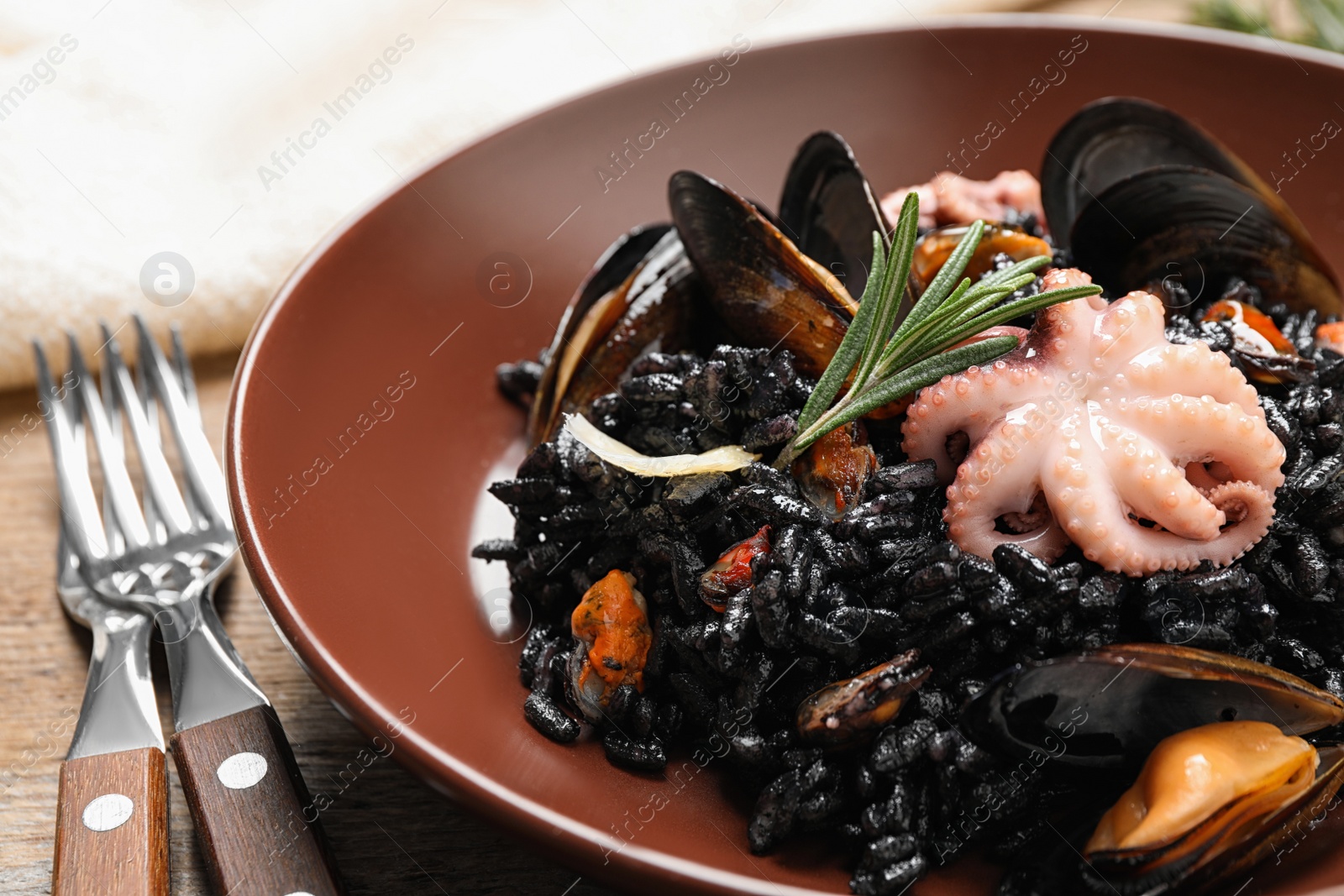 Photo of Delicious black risotto with seafood on wooden table, closeup