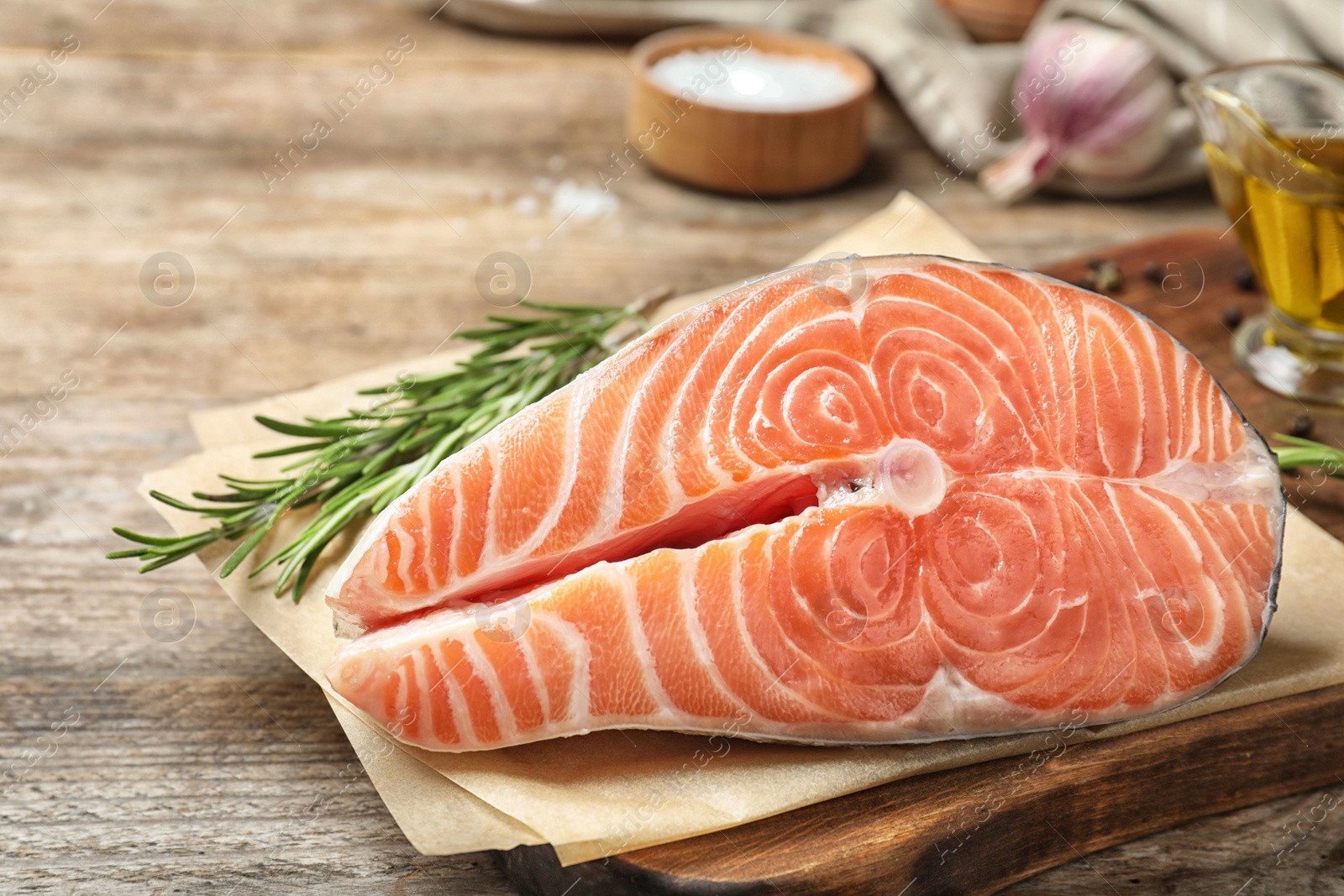 Photo of Fresh raw salmon with rosemary on wooden table. Fish delicacy