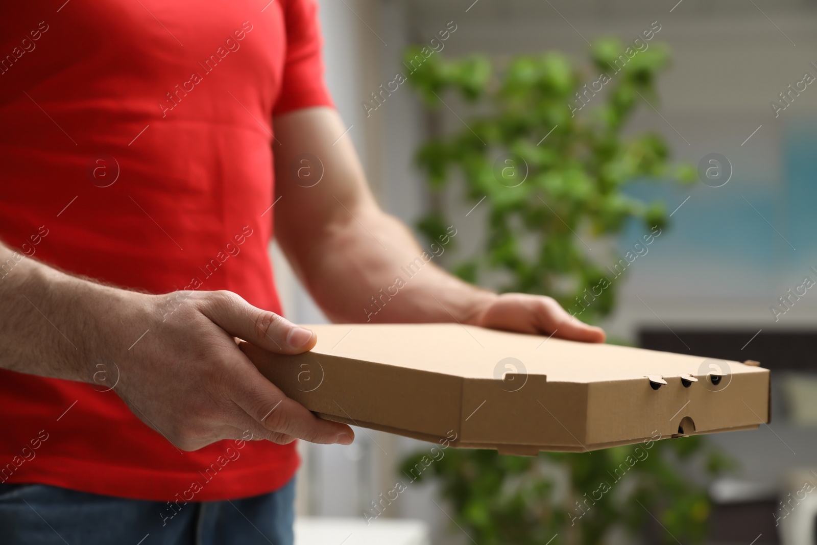 Photo of Courier with pizza box on blurred background, closeup