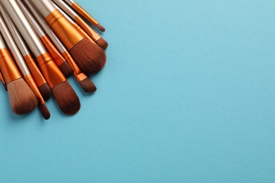 Photo of Set of makeup brushes on light blue background, space for text