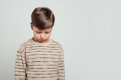 Photo of Upset boy on light grey background, space for text. Children's bullying