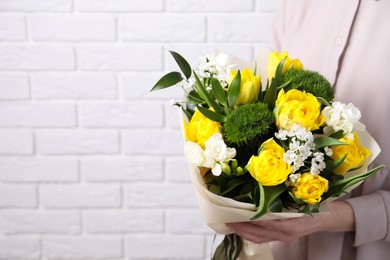 Photo of Woman with bouquet of beautiful tulips near white brick wall, closeup. Space for text