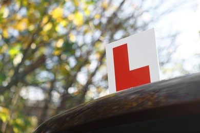 Photo of L-plate on car outdoors, space for text. Driving school