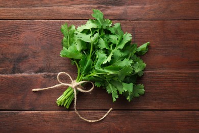 Photo of Bunch of fresh coriander on wooden table, top view