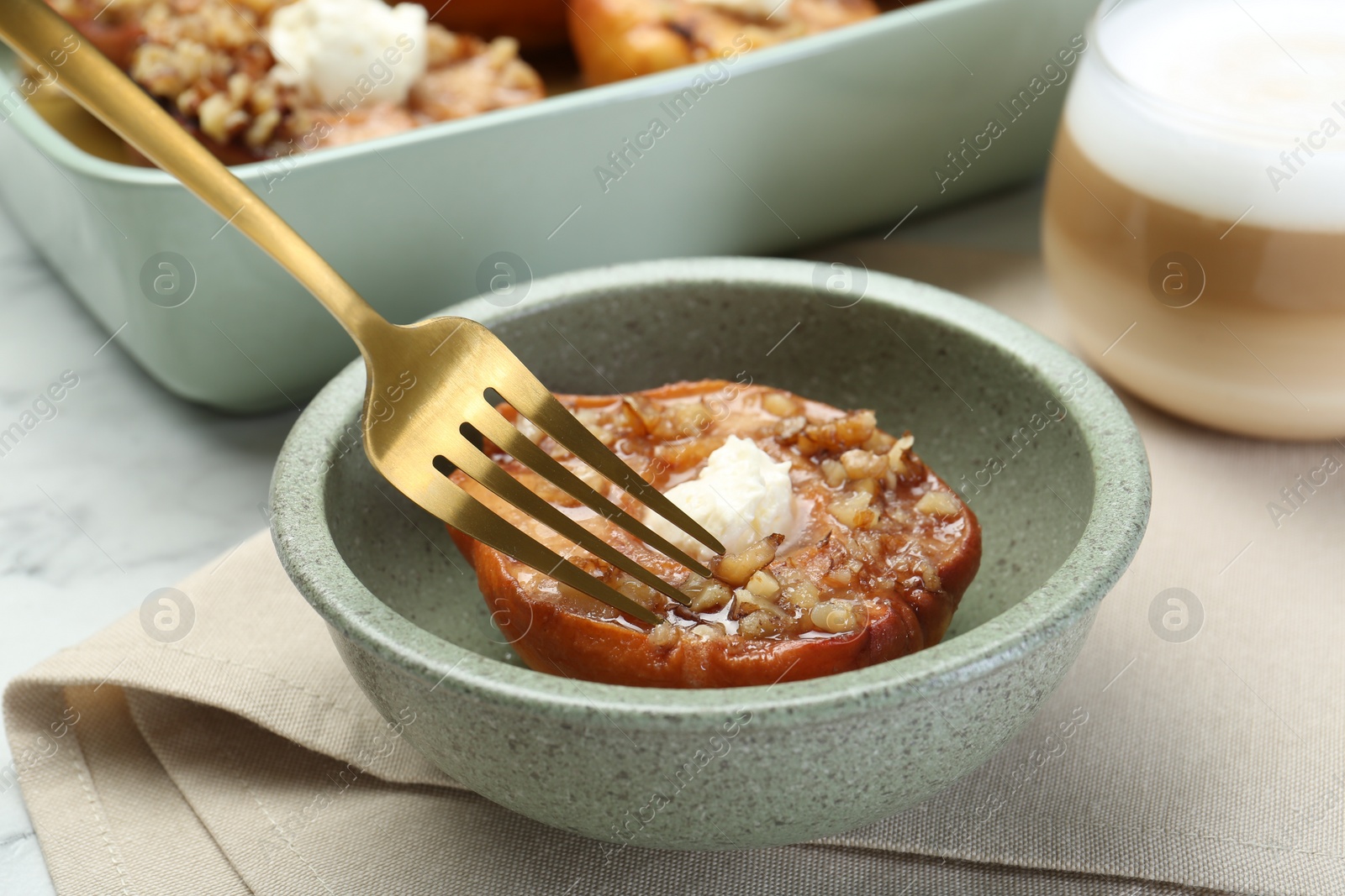 Photo of Eating tasty baked quince with nuts and cream cheese at table, closeup