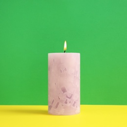 Alight scented wax candle on color background