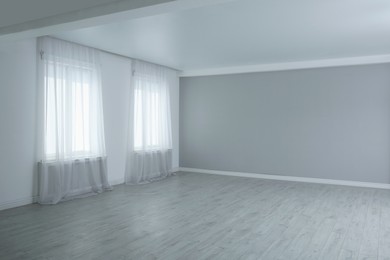 Empty room with large windows and laminated floor