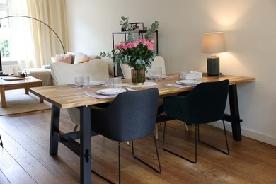 Photo of Beautiful table setting with bouquet in dining room. Roses and eucalyptus branches in vase