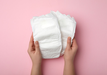 Photo of Woman with diapers on pink background, closeup