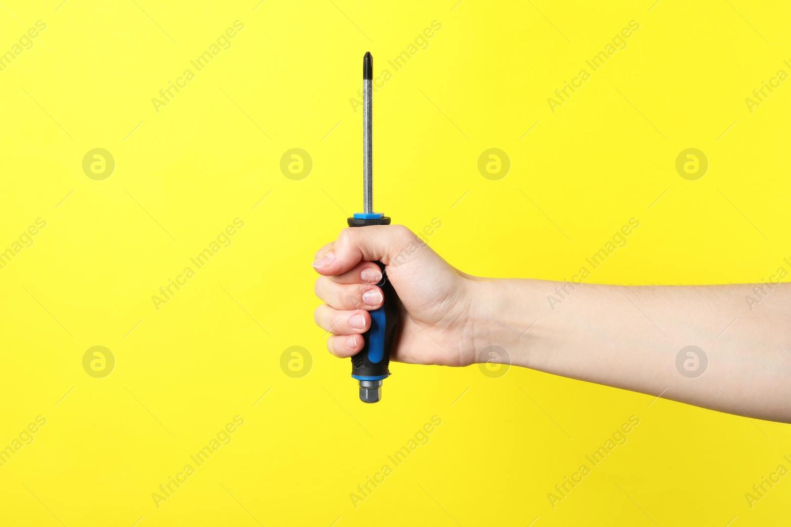 Photo of Woman holding screwdriver on yellow background, closeup