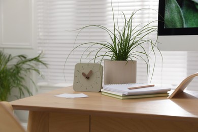 Notebooks, clock and houseplant on table in room