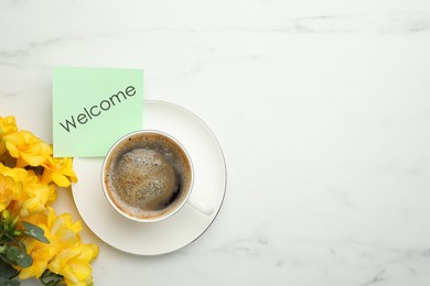 Welcome card, beautiful yellow freesia flowers and cup of aromatic coffee on white marble table, flat lay