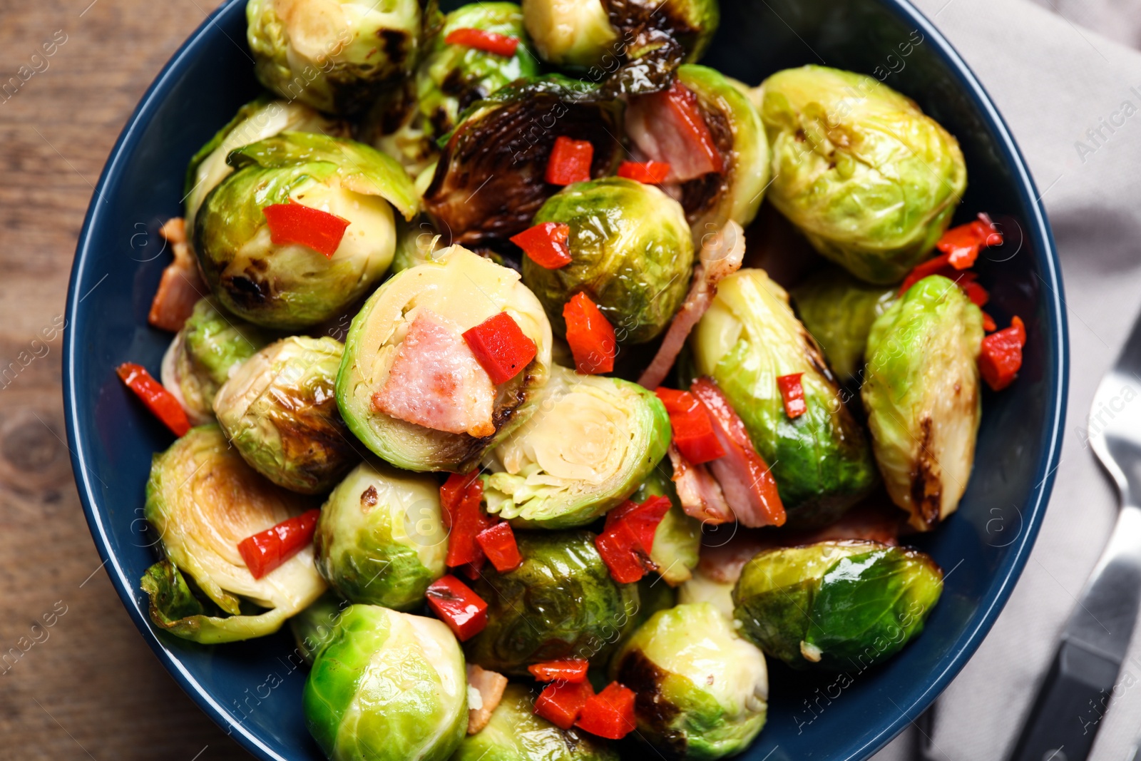 Photo of Delicious Brussels sprouts with bacon in bowl, closeup