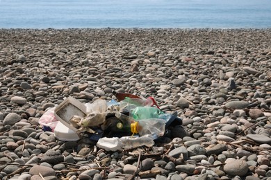 Photo of Pile of garbage on pebble beach near sea. Environmental Pollution concept