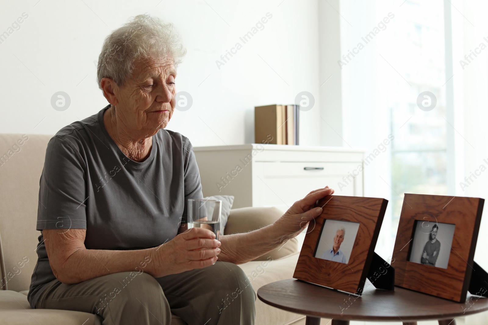 Photo of Elderly woman with framed photos at home