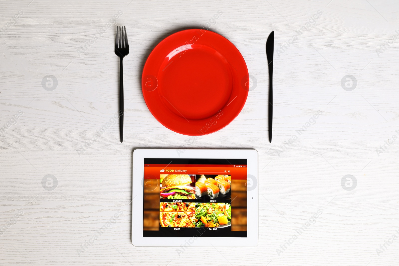 Photo of Modern tablet with open page for online food ordering, plate and cutlery on white wooden table, flat lay. Concept of delivery service