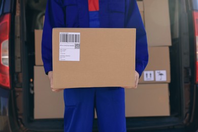 Courier with parcel near delivery van outdoors, closeup