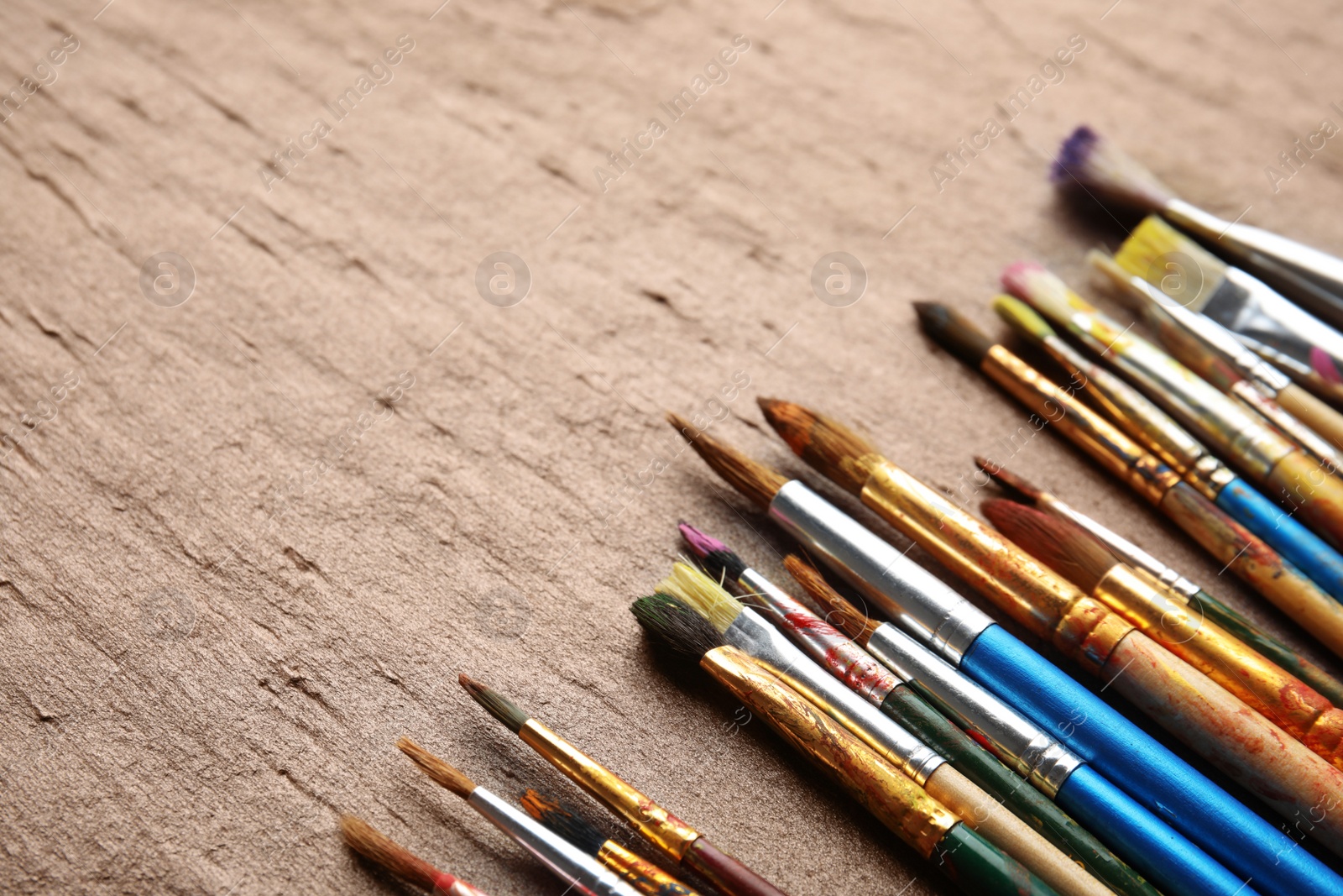 Photo of Different bright paint brushes on color table. Space for text