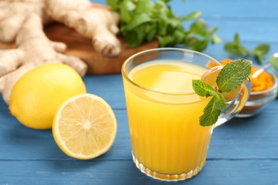 Photo of Immunity boosting drink and ingredients on blue wooden table, closeup