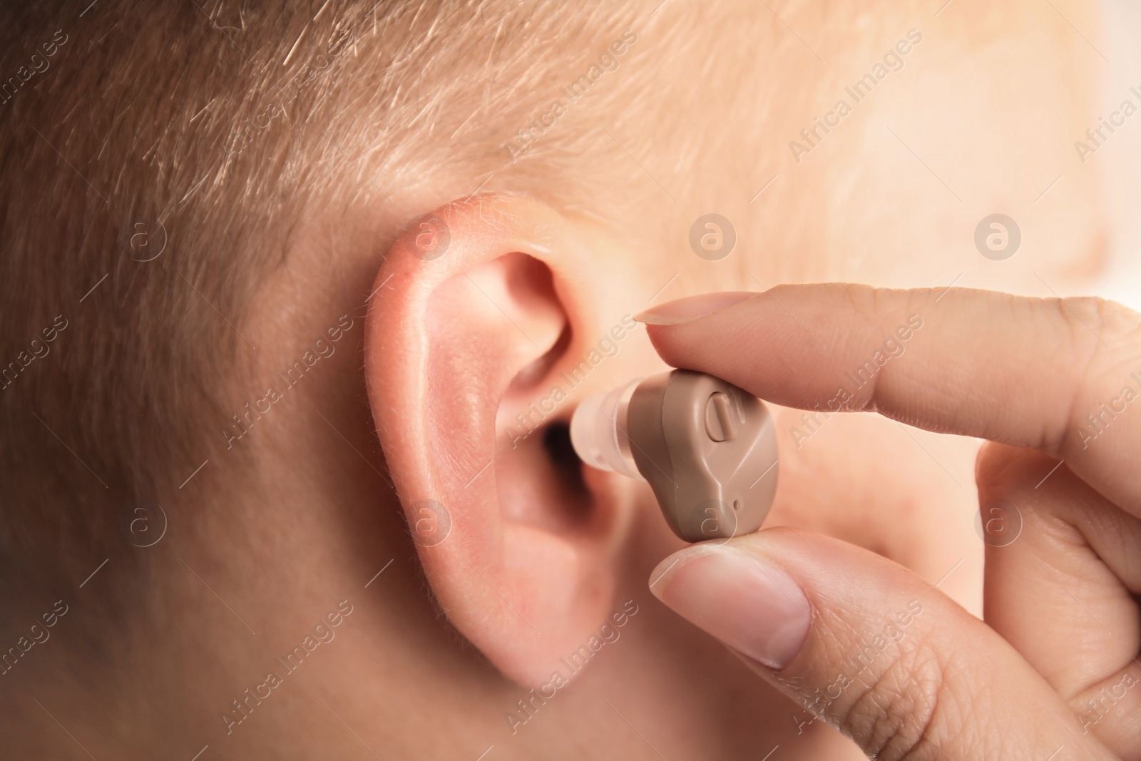 Photo of Doctor putting hearing aid in patient's ear, closeup