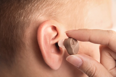 Photo of Doctor putting hearing aid in patient's ear, closeup