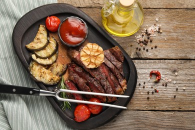 Photo of Delicious grilled beef steak with vegetables and spices on wooden table, flat lay