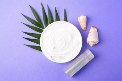 Photo of Jar of cream, green leaf, seashells and shampoo sample on violet background, flat lay