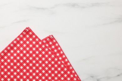 Photo of Red checkered tablecloth on white marble table, top view. Space for text