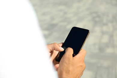 Photo of Man using modern mobile phone outdoors, closeup