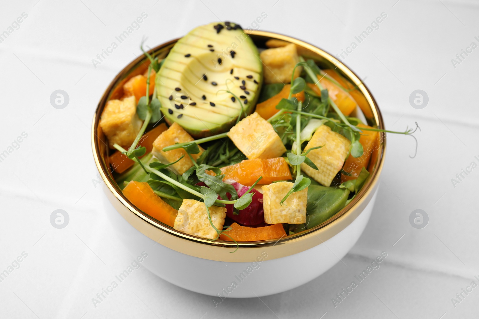 Photo of Delicious salad with tofu and vegetables on white tiled table, closeup