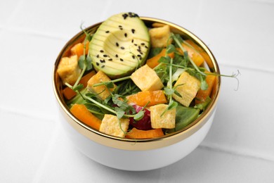 Delicious salad with tofu and vegetables on white tiled table, closeup