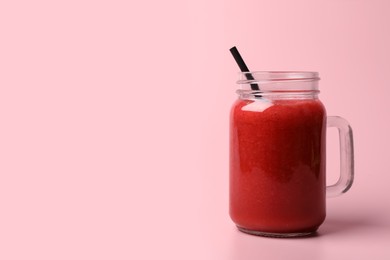 Mason jar with delicious berry smoothie on pink background. Space for text