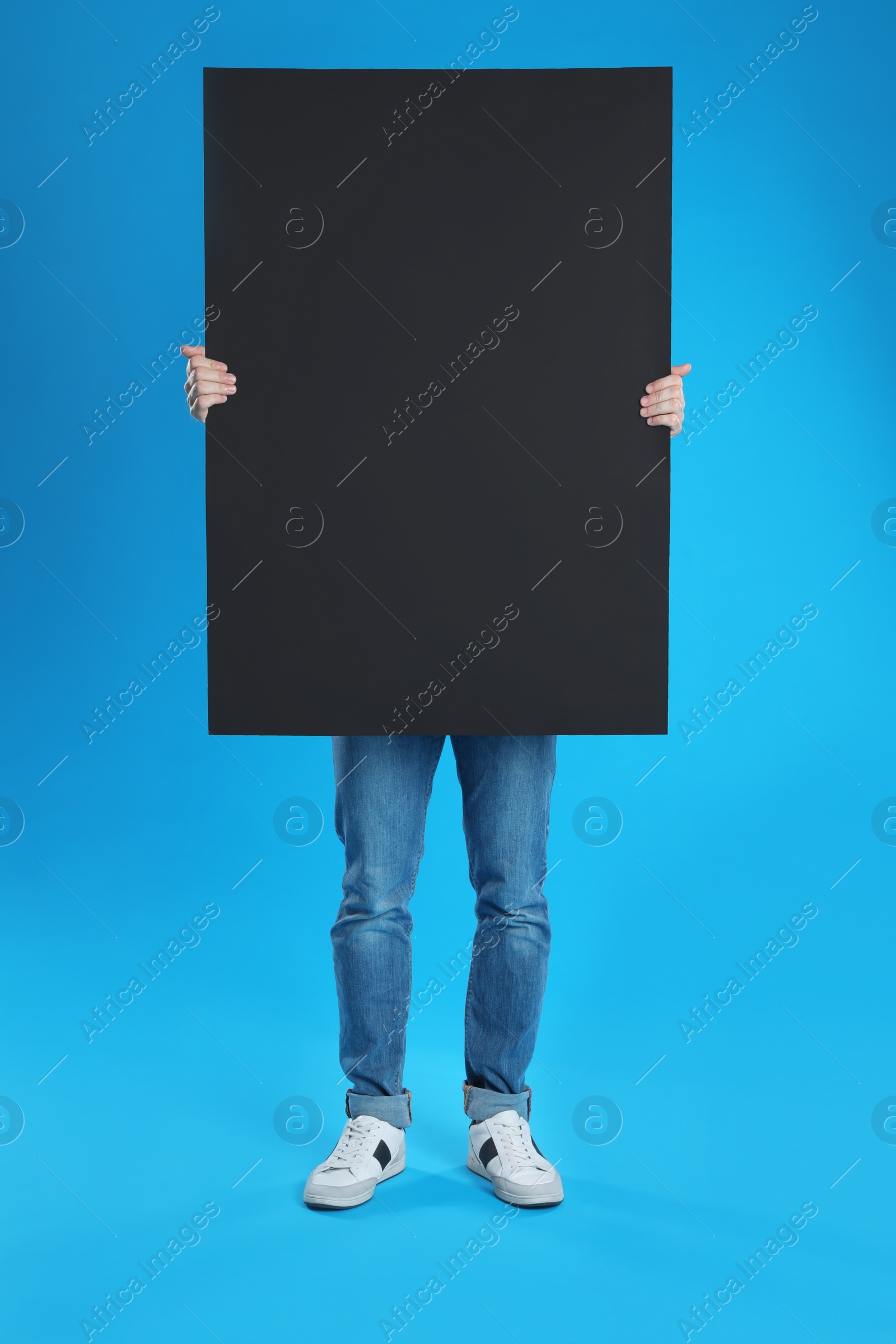 Photo of Man holding blank poster on blue background