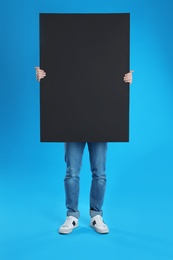 Photo of Man holding blank poster on blue background