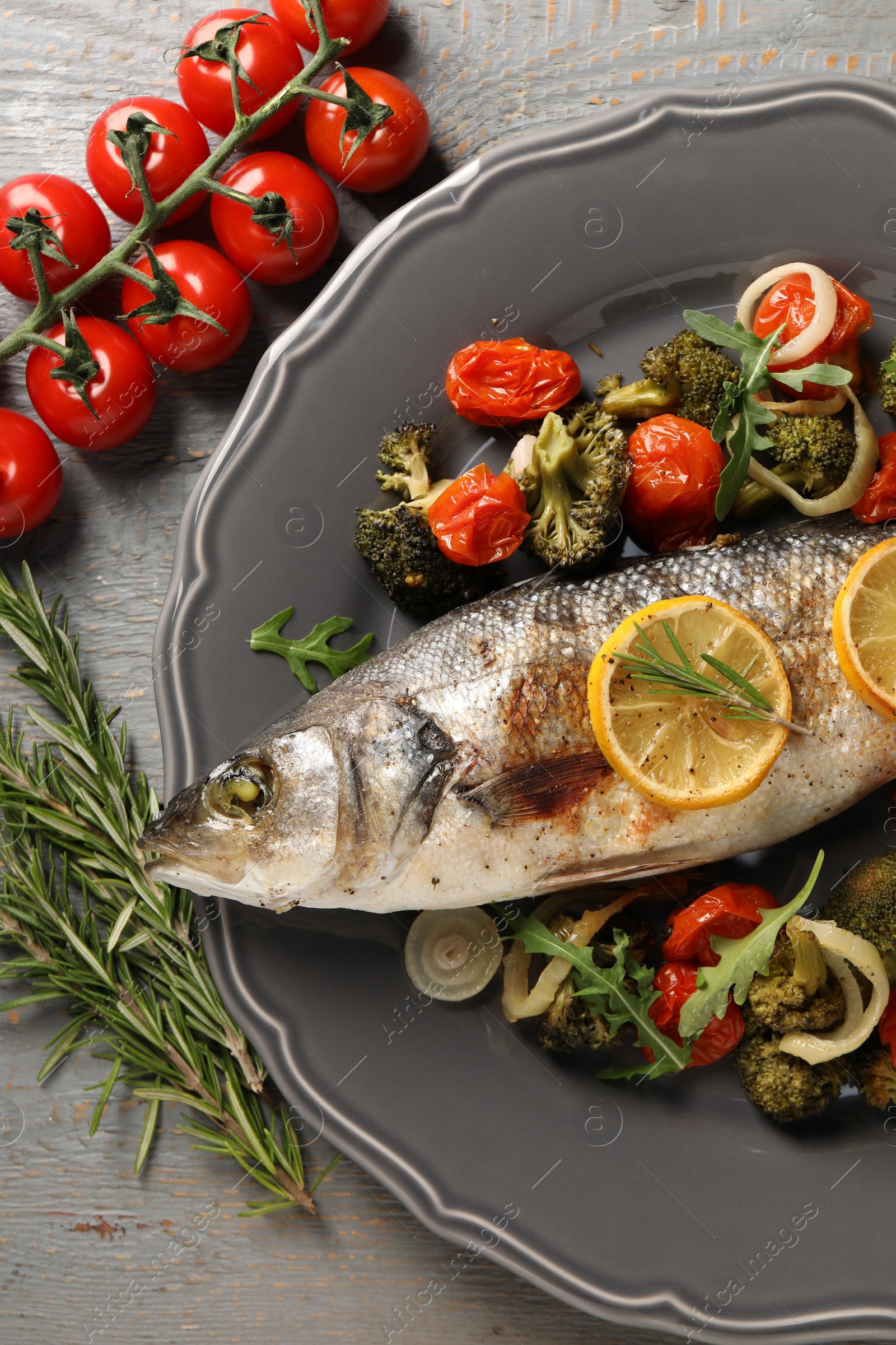 Photo of Baked fish with vegetables, rosemary and lemon on grey wooden table, flat lay