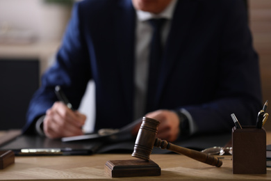 Photo of Male lawyer working at table in office, focus on gavel