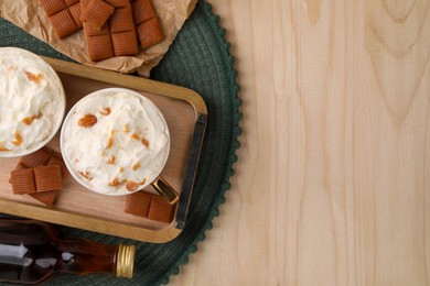 Photo of Delicious coffee with whipped cream and caramel syrup on wooden table, flat lay. Space for text