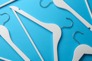 Photo of White hangers on light blue background, flat lay
