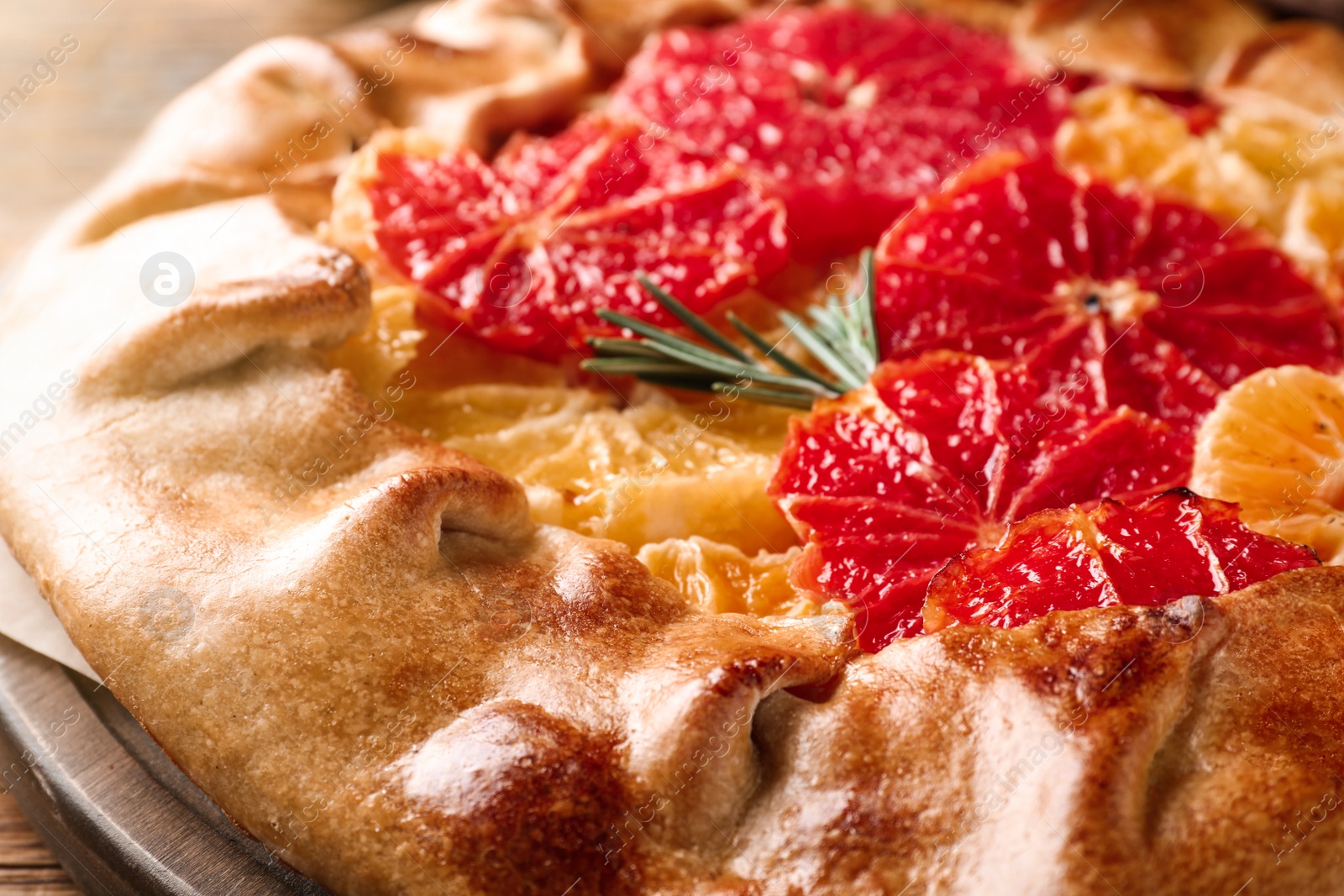 Photo of Tasty galette with citrus fruits and rosemary, closeup